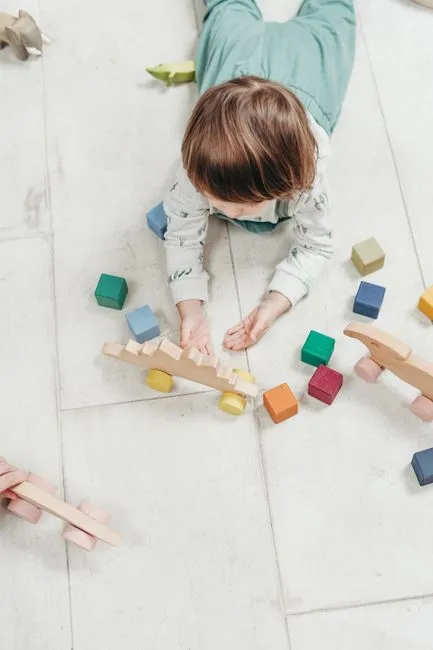 A toddler joyfully playing with a colorful sensory bin filled with pasta, scoops, and small animal t